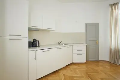 a white kitchen with white cabinets and a wooden floor at Wenceslas Square Residence in Prague