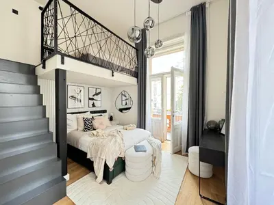 a bedroom with a large bed and a staircase at Rentero Modern High Ceiling Loft with Terrace Apartment, Prague in Prague