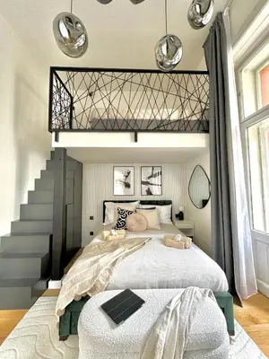 a bedroom with a large bed and a staircase at Rentero Modern High Ceiling Loft with Terrace Apartment, Prague in Prague