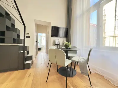 a dining area with a table and chairs in a room at Rentero Modern High Ceiling Loft with Terrace Apartment, Prague in Prague