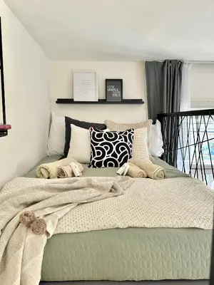 a bedroom with a bed with blankets and pillows at Rentero Modern High Ceiling Loft with Terrace Apartment, Prague in Prague