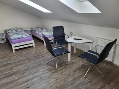 a room with two beds and a table and chairs at Komárov Apartment in Beroun