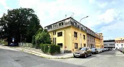 a yellow building with cars parked in front of it at Hillside Studios in Prague