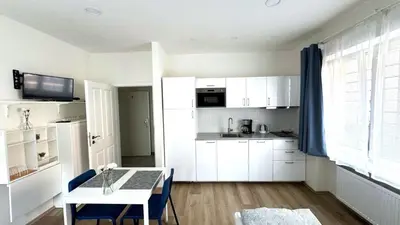 a kitchen with white cabinets and a white table and a table and a table at Hillside Studios in Prague