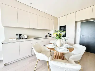 a kitchen with white cabinets and a table and chairs at Rentero Modern, River View Apartment near Prague City Center in Prague