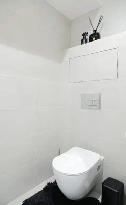 a bathroom with a white toilet and a black rug at Rentero Modern, River View Apartment near Prague City Center in Prague