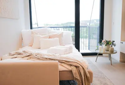 a bedroom with a bed with white pillows and a balcony at Rentero Modern, River View Apartment near Prague City Center in Prague