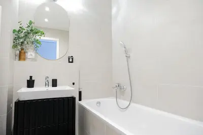 a bathroom with a sink and a tub and a mirror at Rentero Modern, River View Apartment near Prague City Center in Prague