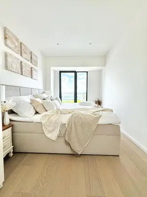 a white bedroom with a large bed with a window at Rentero Modern, River View Apartment near Prague City Center in Prague