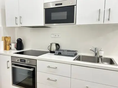 a white kitchen with a sink and a microwave at Entire unit in the center of Prague in Prague