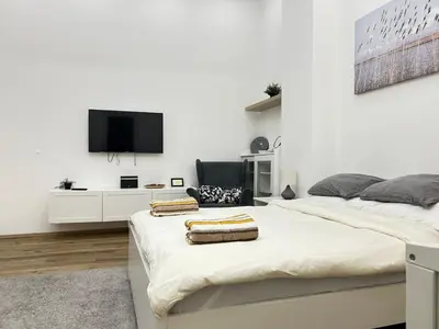 a white bedroom with two beds and a flat screen tv at Entire unit in the center of Prague in Prague