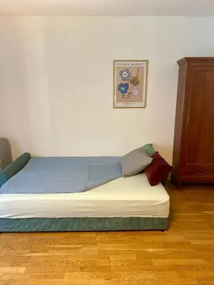 a bed sitting in a room with a wooden floor at Pegas Apartments in Prague