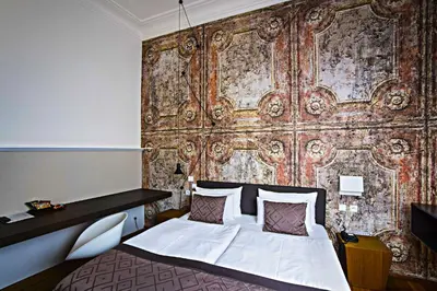 a bedroom with a bed in front of a wall at Hotel Golden Crown in Prague