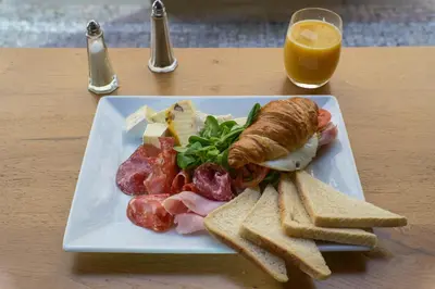 a plate of food with a sandwich and bread and a glass of orange juice at Hotel Golden Crown in Prague