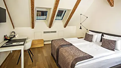 a hotel room with a bed and a desk and windows at Hotel Golden Crown in Prague