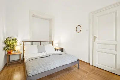 a white bedroom with a bed and a mirror at Prague Hostel Apartments in Prague