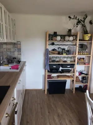 a kitchen with white cabinets and a wooden floor at Chalupa Kokorinsko in Mšeno