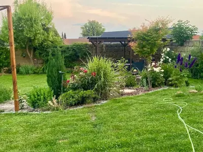 a garden with green grass and flowers and a gazebo at Chalupa Kokorinsko in Mšeno