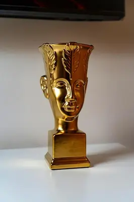 a gold vase with a face on it on a table at River Deluxe Suite in Prague