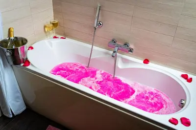a bath tub filled with pink water in a bathroom at Golden River Apartment in Prague