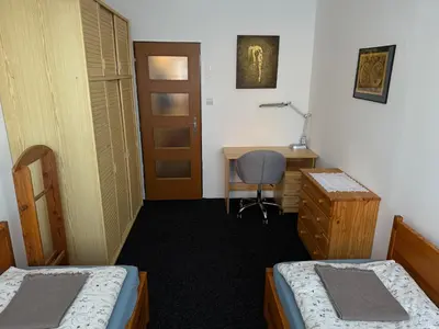 a room with two beds and a desk and a door at Apartmán Kamýk in Prague