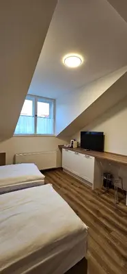 a attic room with two beds and a television at Hotel Karlova Prague in Prague