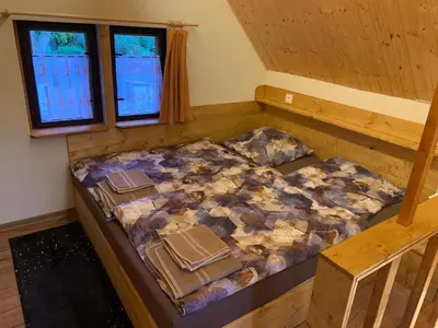 a large bed in a room with two windows at Chata Mareš in Samechov