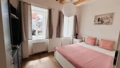 a bedroom with a bed with pink sheets and two windows at Četnická Stanice Mšeno in Mšeno