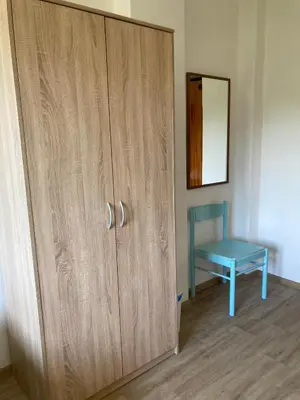 a wooden cabinet with a blue stool next to a mirror at Penzion Cholín in Nový Knín