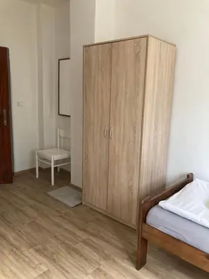 a bedroom with a wooden cabinet and a bed at Penzion Cholín in Nový Knín
