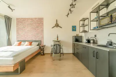 a bedroom with a bed and a kitchen with a sink at IndustriaLux Suite by Rentez in Prague