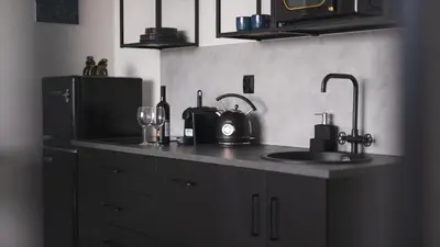 a kitchen with a counter with a sink and a refrigerator at IndustriaLux Suite by Rentez in Prague