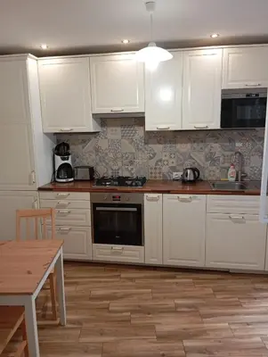 a white kitchen with white cabinets and a wooden table at Prague centrum house in Prague
