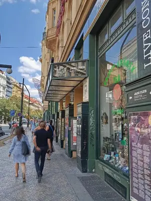 people walking down a street in front of shops at Prague centrum house in Prague