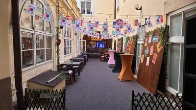 a corridor of a building with tables and chairs and flags at Koreatown in Prague