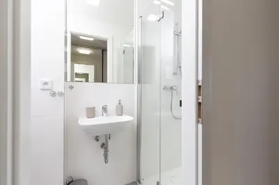 a white bathroom with a sink and a shower at SKYLINE PRAGUE Apartments in Prague
