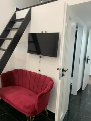 a red couch with a flat screen tv on a wall at T1-Wenceslas square in Prague