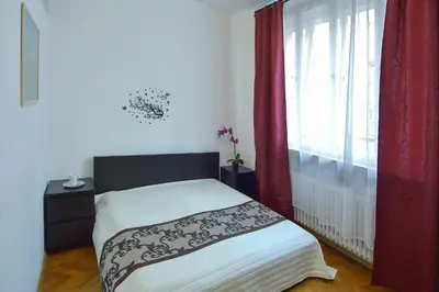a bedroom with a bed and a window with red curtains at Modern Apartment Navrátilova II in Prague