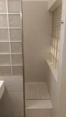a white tiled shower with a bench in a bathroom at Modern Apartment Perlova in Prague