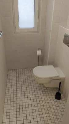 a white tiled bathroom with a toilet and a window at Modern Apartment Perlova in Prague