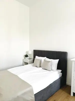a white bedroom with a large bed with white sheets and pillows at Apartman Namesti Miru in Prague