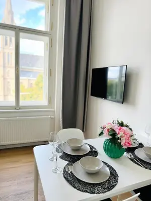 a white table with plates and glasses and a vase of flowers at Apartman Namesti Miru in Prague