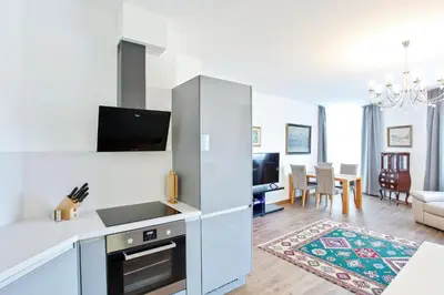 a kitchen with white cabinets and a living room at Melody in Prague