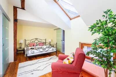 a living room with a red chair and a bed at Spacious apartments near National theatre in Prague