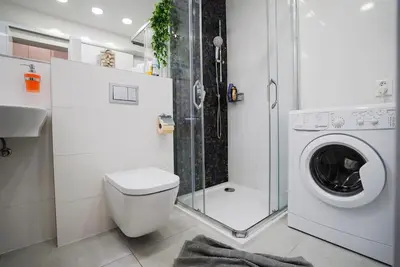 a bathroom with a washing machine and a shower at Cozy apartment with garage in Prague
