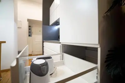 a kitchen with white cabinets and a trash can at Cozy apartment with garage in Prague