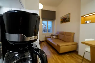 a coffee maker in a kitchen with a living room at Cozy apartment with garage in Prague