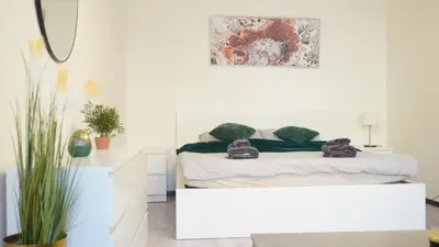 a white bedroom with a bed and a mirror at Flat with Balcony and Garage in Prague