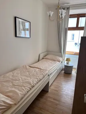 a small bed in a room with a window at New City Centre Garden Apartment - Central Location in Prague