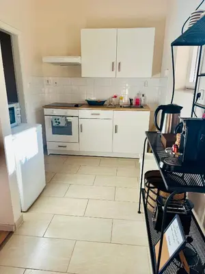 a kitchen with white cabinets and a tiled floor at Nature Nest in Prague